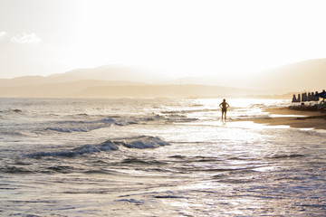 Fototapeta na wymiar Woman in the rays of the rising sun on the beach.