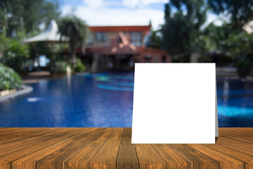 white card put on wood table and beautiful view of swiming pool at resort in background. product display template. Business presentation.clipping path include