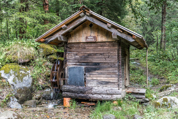 Fototapeta na wymiar Kleine Wassermühle im Wald zwischen Bäumen und Felsbrocken