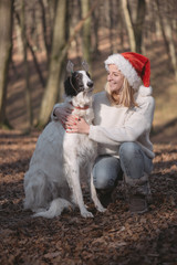 Young woman in santa hat posing outdoor with cute dog