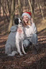 Young woman in santa hat posing outdoor with cute dog