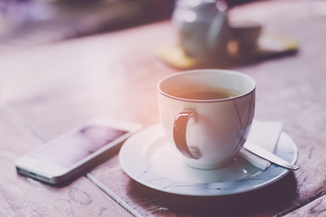 Mobile phone and coffee cup on office wooden table