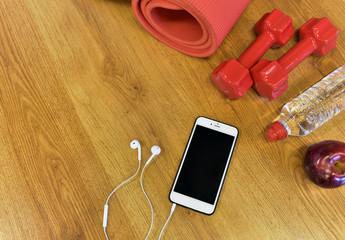 Fitness concept with dumbbells, water, apple and music