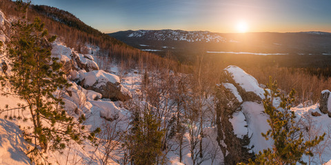 Fototapeta na wymiar Beautiful Ural winter landscape with the setting sun over the mountain, the snow-covered woods and rocks