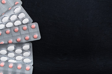 Various tablets pills in blister pack. Medicines on black background, top view