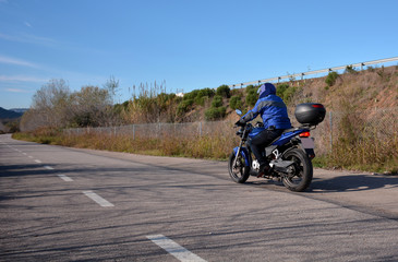 Obraz premium biker with helmet blue going by a road