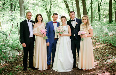 happy and beautiful newlyweds and their bridesmaids standing tog