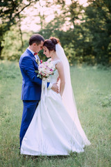 beautiful and young groom and bride standing together outdoors