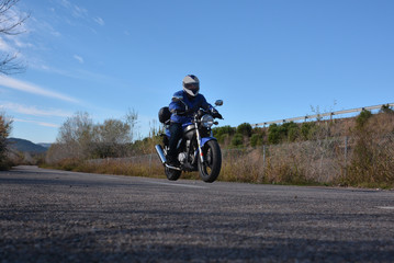 Fototapeta na wymiar biker with helmet blue going by a road