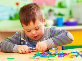 cute kid with down's syndrome playing in kindergarten - 128843613