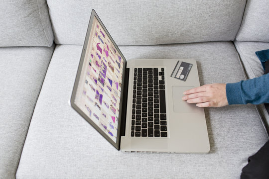 a young woman on a couch, ordering items online with her laptop and creditcard