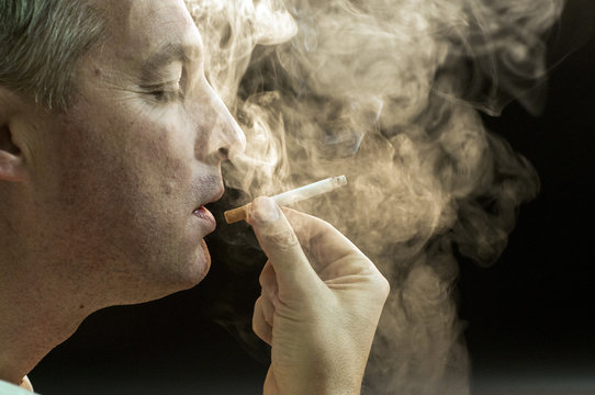 Man smoking against a black background, Cigarette addiction. 