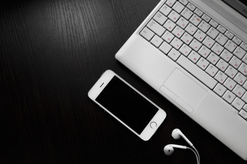 White laptop with laptop and phone on a black background for business and work

