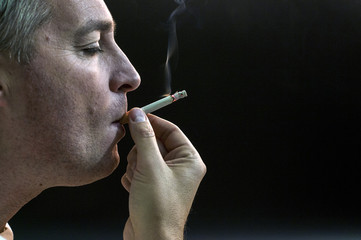 Obraz premium Man smoking cigarette on black background, Handsome young man smoking