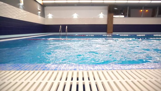 Girl child swimmer in a red bathing suit on a background of the pool inside the room with glasses and a cap.