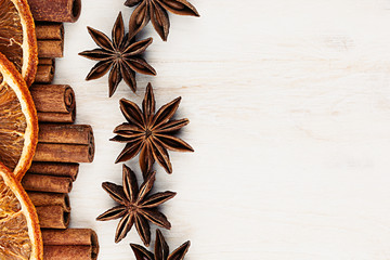 Cinnamon sticks, anise star and oranges closeup on white wood background. Christmas decorative border of cinnamon sticks spice. Top view.