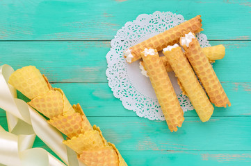 Tender honey wafers in the form of tubes, stuffed with air cream on white lace napkin. The top view