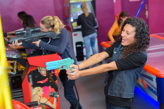 Women firing guns playing arcade game