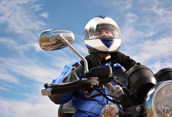 biker with helmet blue going by a road