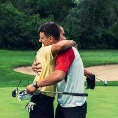 Golfers having friendly hug after game