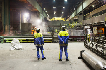 workers of a steel factory look at the manufacturing process
