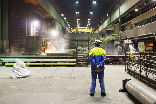 workers of a steel factory look at the manufacturing process