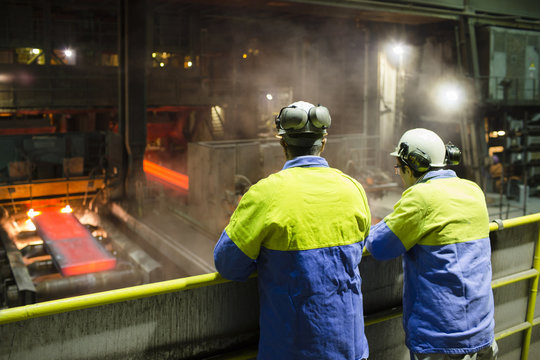 workers of a steel factory look at the manufacturing process
