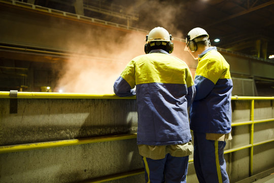 workers of a steel factory look at the manufacturing process