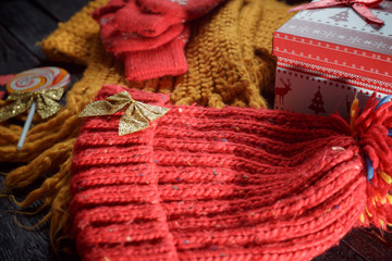 Fototapeta na wymiar red hat and gloves, yellow scarf Christmas ornaments on the wooden background