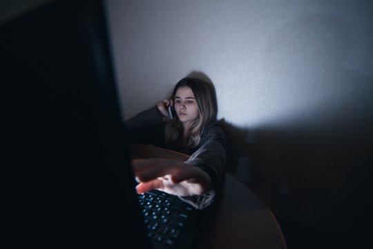 teenager girl sitting at the computer at night. It is a victim of excessive harassment and bullying stalker. she was afraid