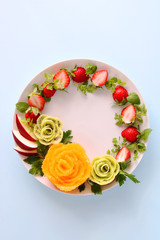 Fototapeta na wymiar Christmas salad with strawberry,apple,rose shaped kiwi fruits and orange フレッシュフルーツのリースサラダ