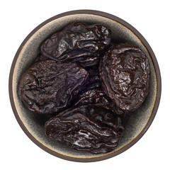 Organic prunes in ceramic bowl isolated on white background, top view