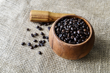 Roasted coffee beans in a wooden mortar on the burlap