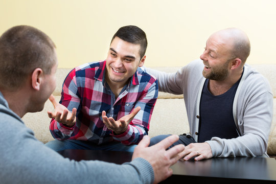 Three male friends talking at home