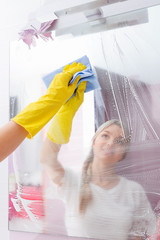 Young lady wiping mirror with special cleaning
