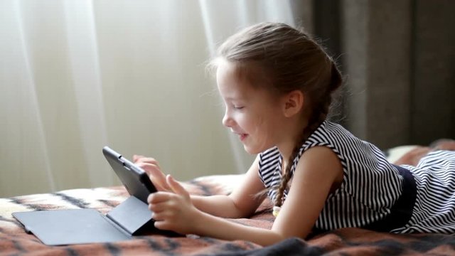 Cute little child girl playing in a tablet computer