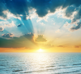 bright sunset in clouds over blue sea