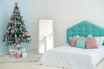 New Year's interior. Christmas tree bed with soft blue back and decorative pillows, large floor mirror