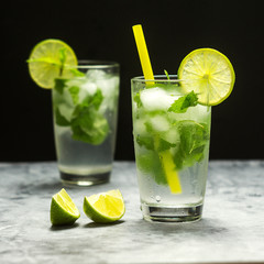 Mojito cocktail with lime and mint in glass on a grey stone background. Square
