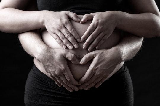 Portrait of parents holding a pregnant belly