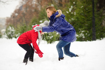 Young woman and girl sculpts snowman.
