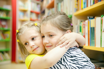Obraz premium little sisters in children's library.