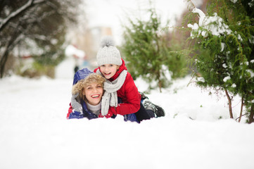 Young woman with daughter of school age lie having embraced on snow.
