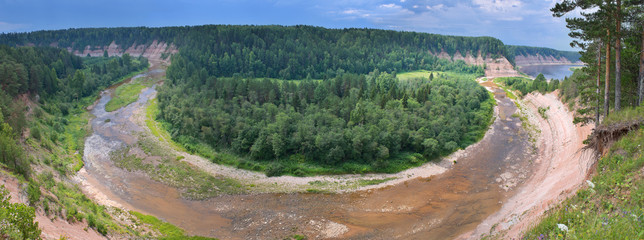 Panorama of twisting river with cool coast in summer sunny day.