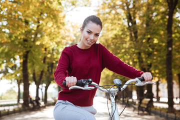 Fototapeta premium Joyful woman dressed in sweater walking with bicycle