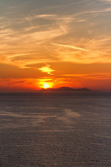 Fototapeta na wymiar Sunset in Oia, Santorini. Sun behind the volcano. Vertical shot