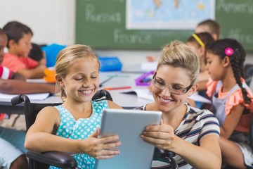 Schoolgirl and teacher using digital tablet in classroom