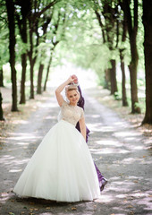 happy and young bride in white dress standing outdoors