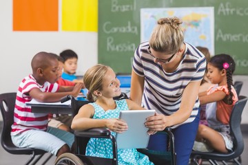 Schoolgirl and teacher using digital tablet in classroom