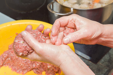 Woman's hand creating meatball for soup in the kitchen. Healthy eating and lifestyle.